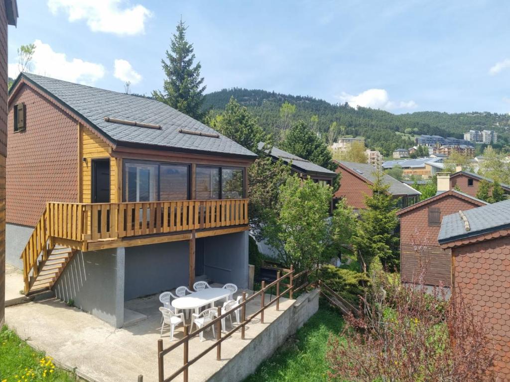 ein Haus mit einer Terrasse und einem Balkon mit Stühlen in der Unterkunft Chalet 8 couchages à 100m du bas des pistes et commerces in Les Angles