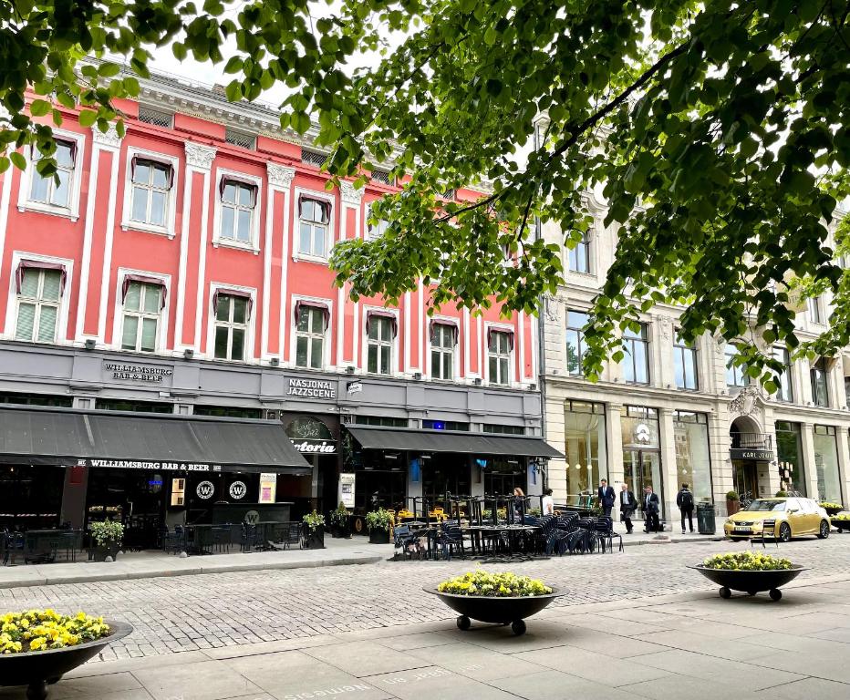 une rue avec un bâtiment rose et deux bols de fleurs dans l'établissement Karl Johans gate 35, à Oslo