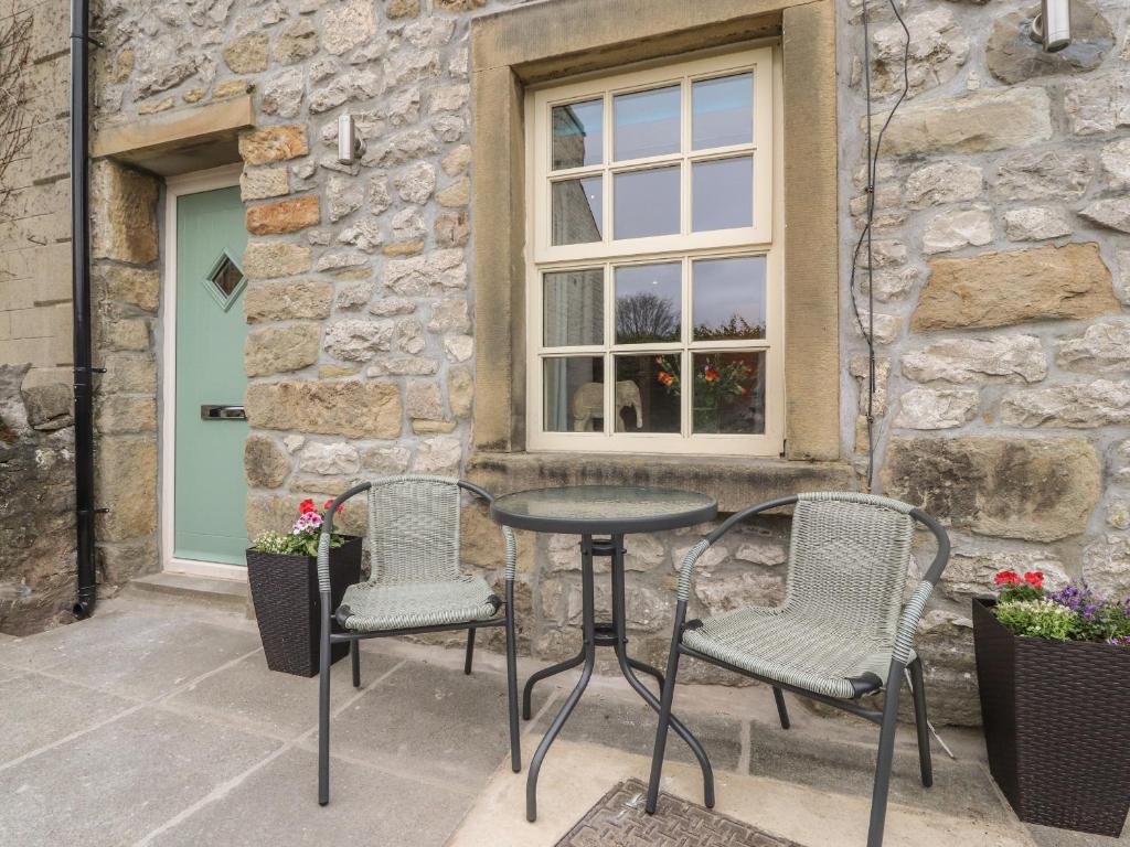 two chairs and a table in front of a building at Folly Cottage in Settle