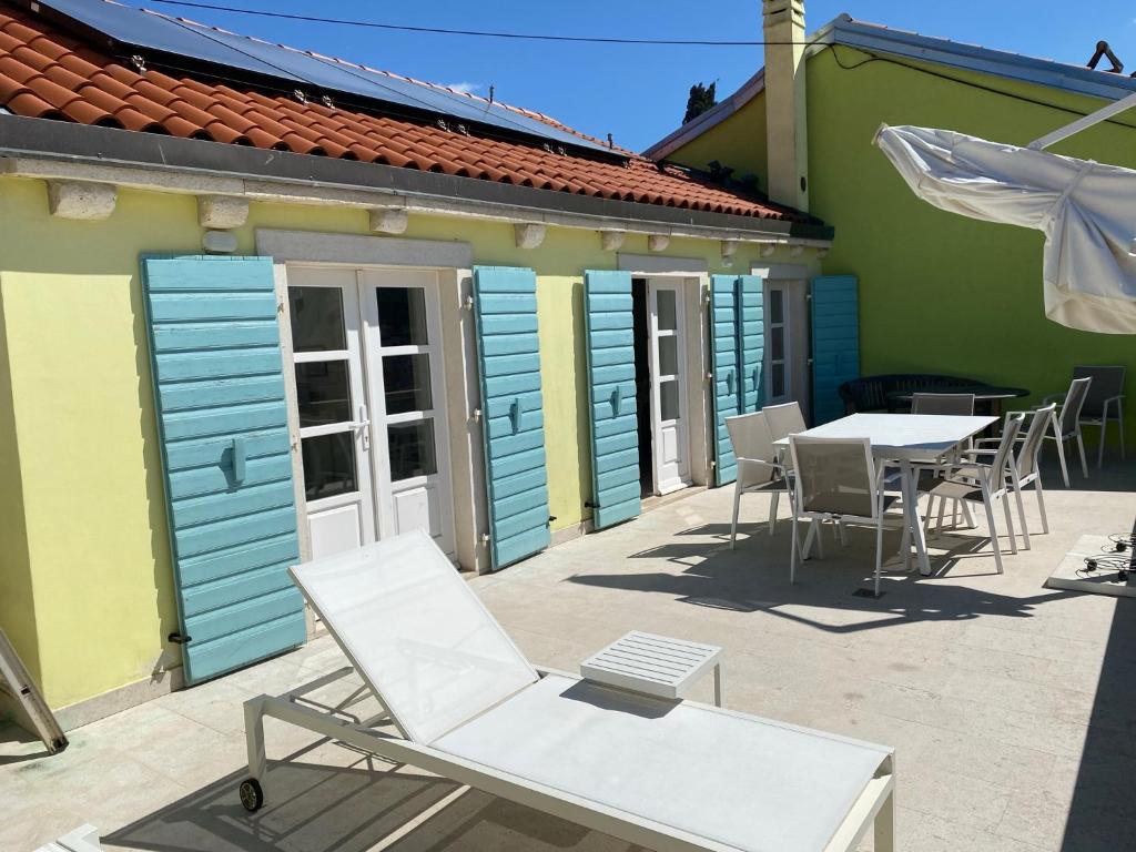 a patio with chairs and tables in front of a building at Spacious 2 storey apartment old town Mali Lošinj in Mali Lošinj