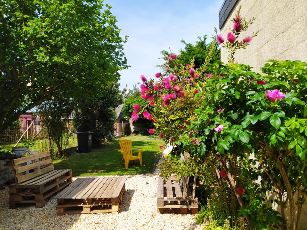 un jardin avec un banc en bois et des fleurs roses dans l'établissement Maison Chic & charme Calme avec Jardin, au Mans