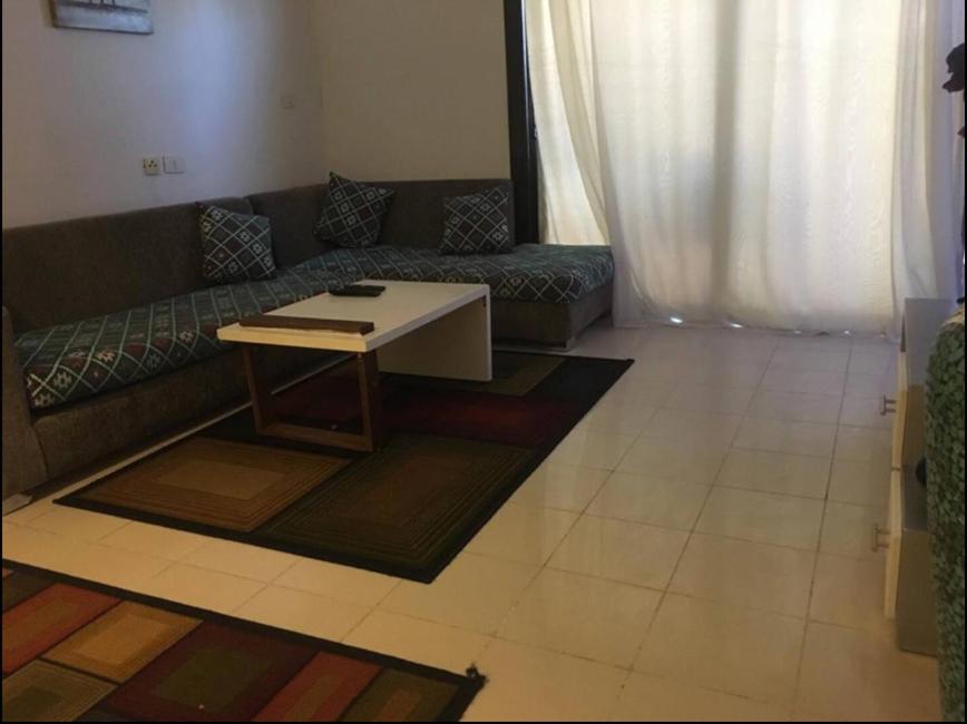 een woonkamer met een bank en een tafel bij Pool view one bedroom - B203 in Hurghada