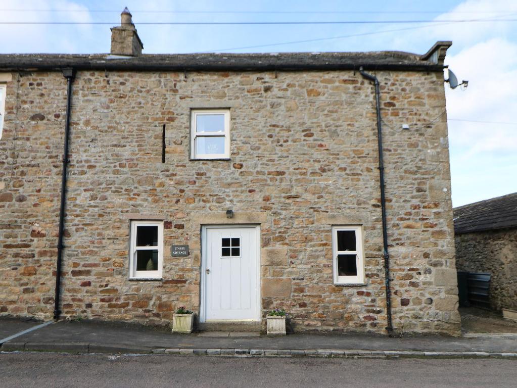 an old brick building with a white door at Stable Cottage in Barnard Castle