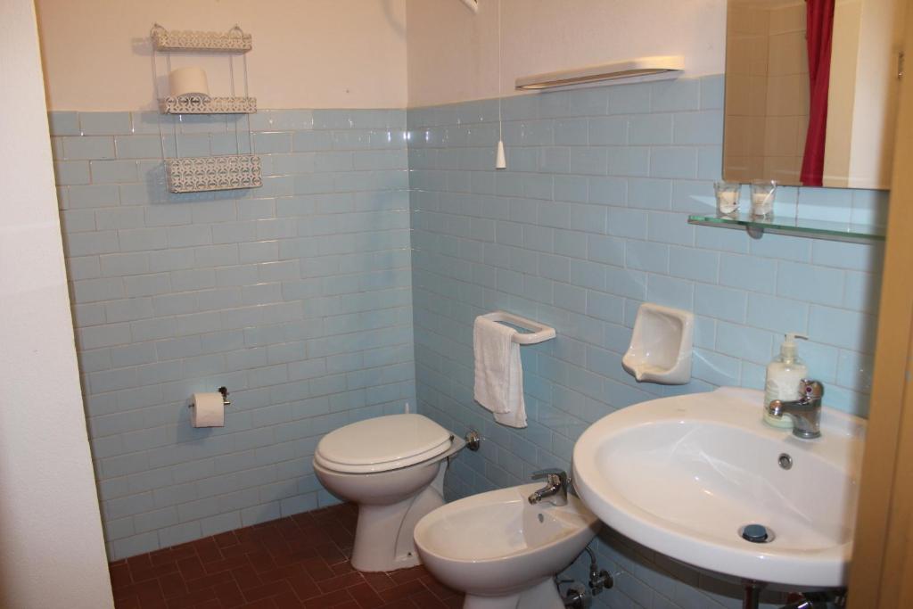 a blue tiled bathroom with a toilet and a sink at Hotel Conca d'Oro in Stalettì