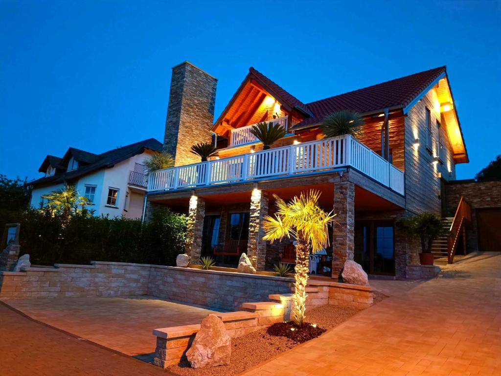 a house with a palm tree in front of it at Luxus Ferienwohnung Chalet Seenähe in Schalkenmehren