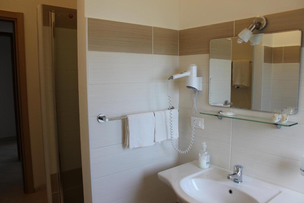 a white bathroom with a sink and a mirror at Hotel Conca d'Oro in Stalettì