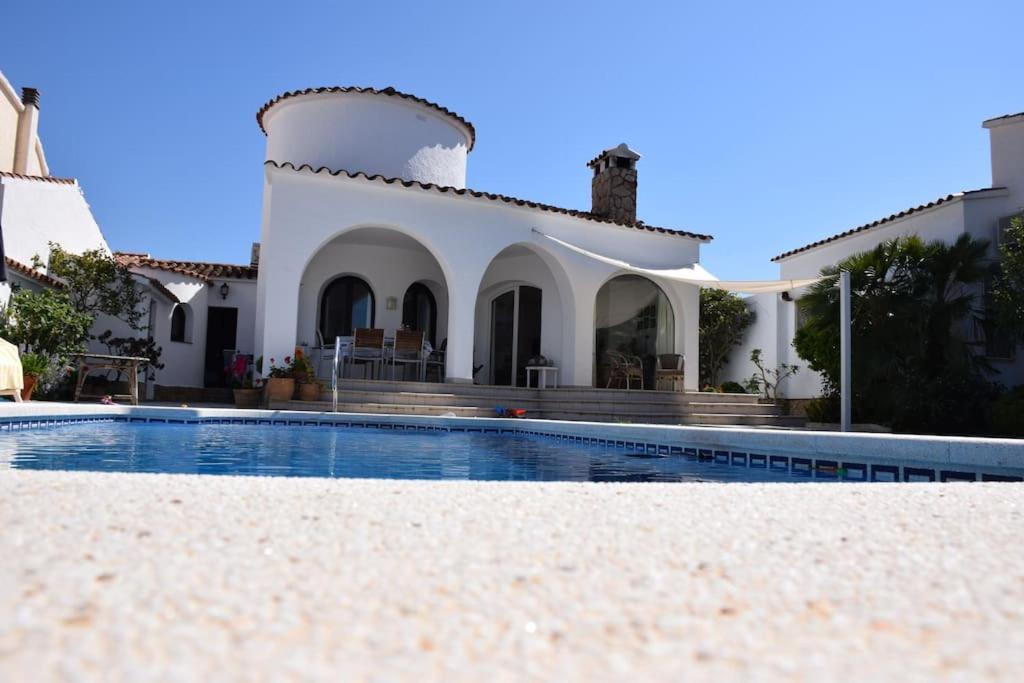 a villa with a swimming pool in front of a house at 'Casa Empuria' aan kanaal met zwembad en aanlegsteiger in Empuriabrava