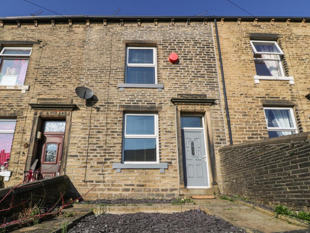 a brick building with a white door and windows at Calder Cottage in Sowerby Bridge
