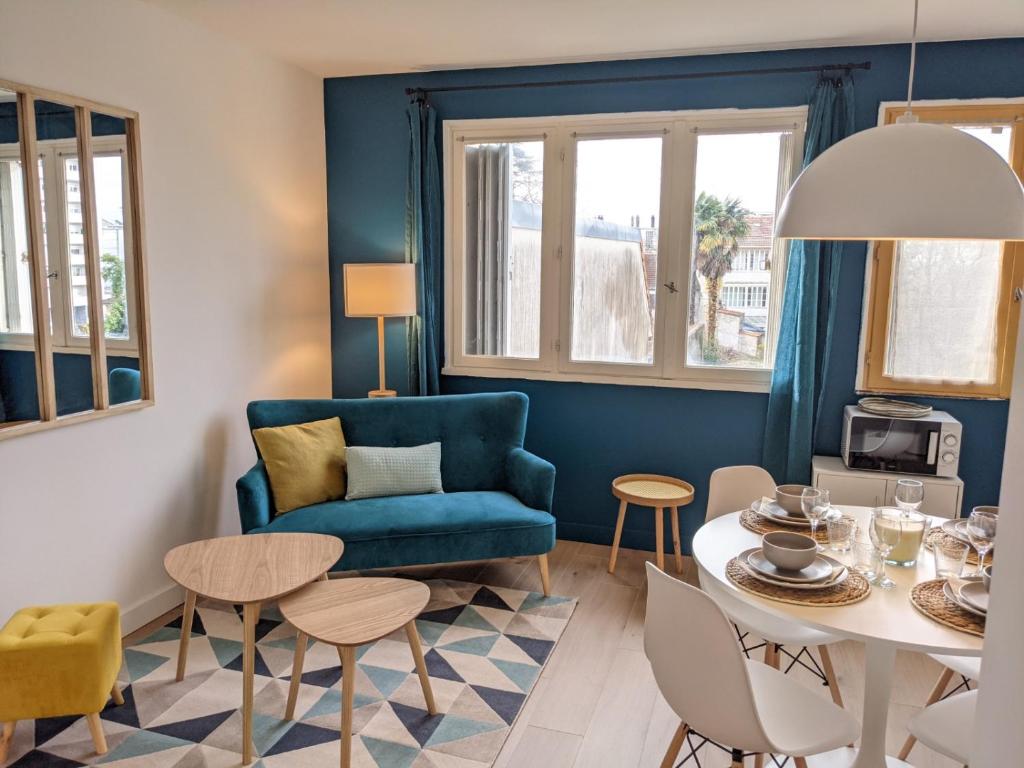 sala de estar con sofá azul, mesa y sillas en Cosy Iris - 3 Ch- Lumineux avec parking gratuit en Pau