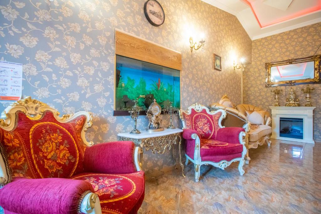 a living room with red chairs and a table and a room with wallpaper at HOTEl MKUDRO in Kutaisi