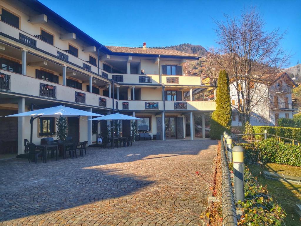 a hotel with tables and umbrellas in a courtyard at Grem Bike Hostel in Premolo