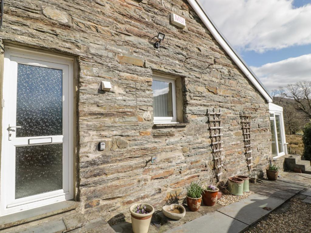 una casa de piedra con plantas a un lado en The Old Smithy Cottage en Blaenau-Ffestiniog