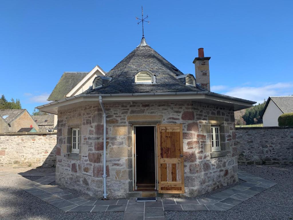 un viejo edificio de piedra con una cruz encima en The Hen House, en Beauly