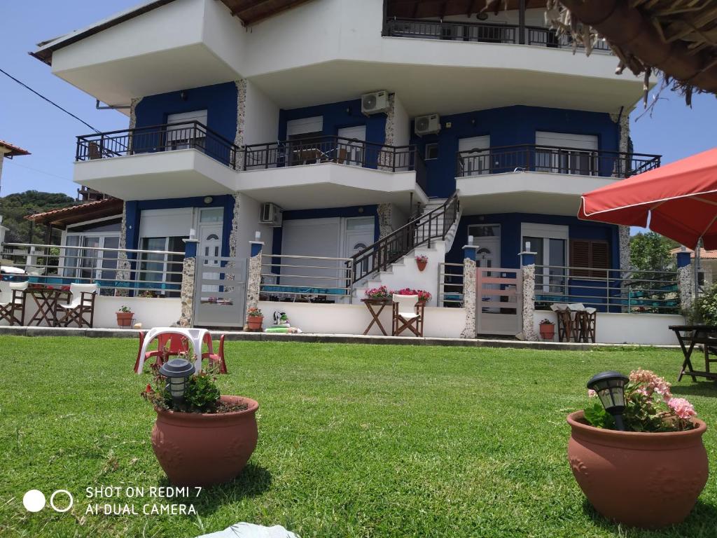 a building with two flower pots in front of it at Rooms Elena in Nea Potidaea