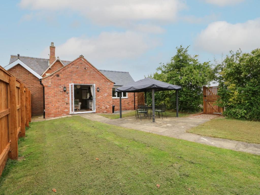 a brick house with a table and an umbrella at The Old Gate House Annexe in Alford