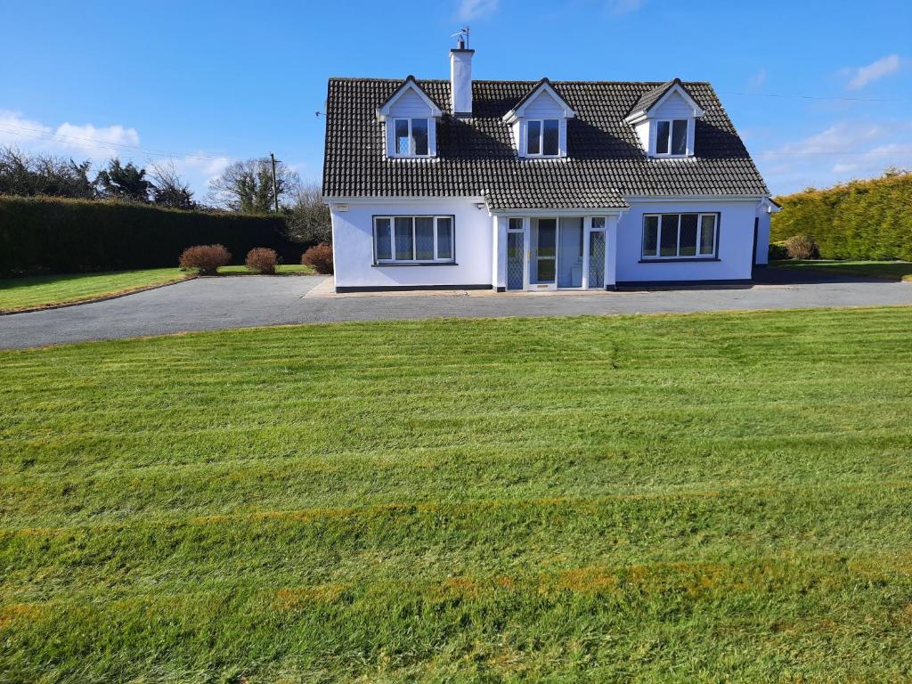 a house with a large green field in front of it at 4 Bedroom, 15 min to Limerick city Quiet Retreat. in Limerick