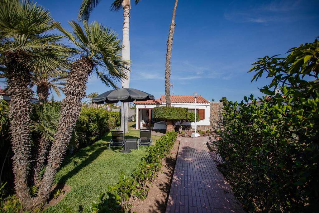 un patio con palmeras y una pasarela con sombrilla en Bungalows Deluxe Las Vegas Golf, en Maspalomas