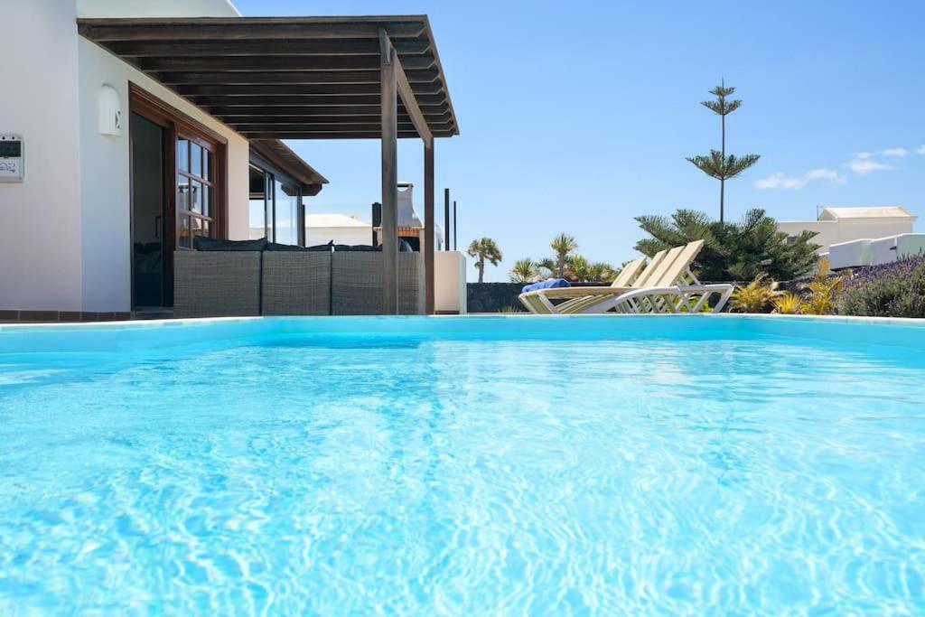 une grande piscine en face d'une maison dans l'établissement Hipoclub Villas, Aguamarina 30, à Playa Blanca