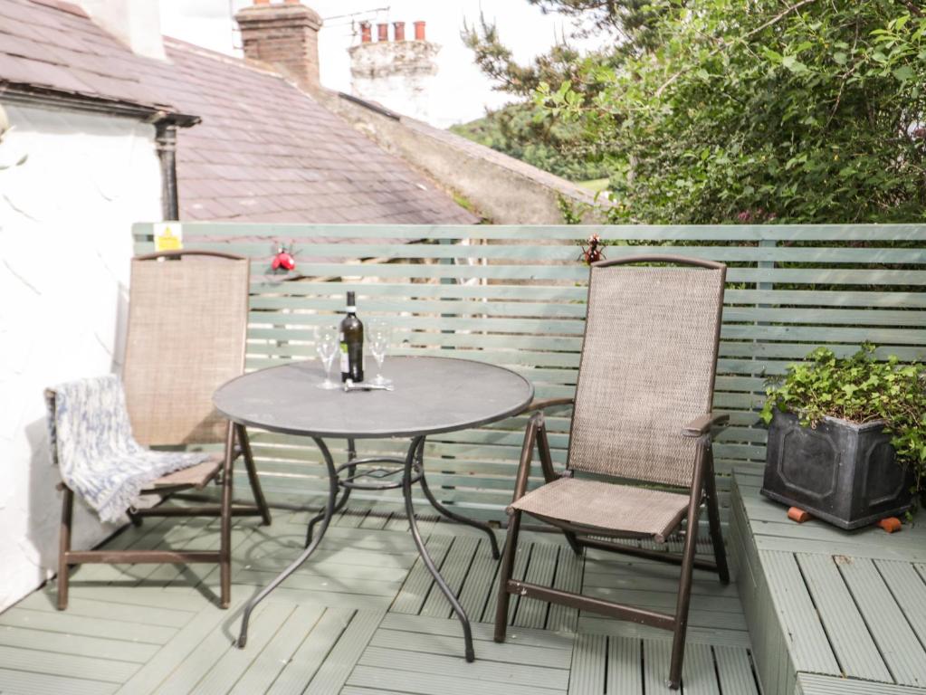 una mesa y sillas en una terraza con una botella de vino en 7 Watkin Street, en Conwy