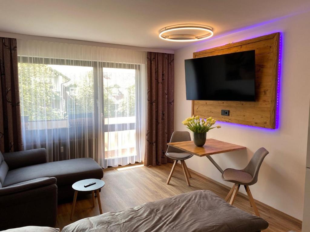 a living room with a tv and a table with chairs at Haus München in Bad Griesbach