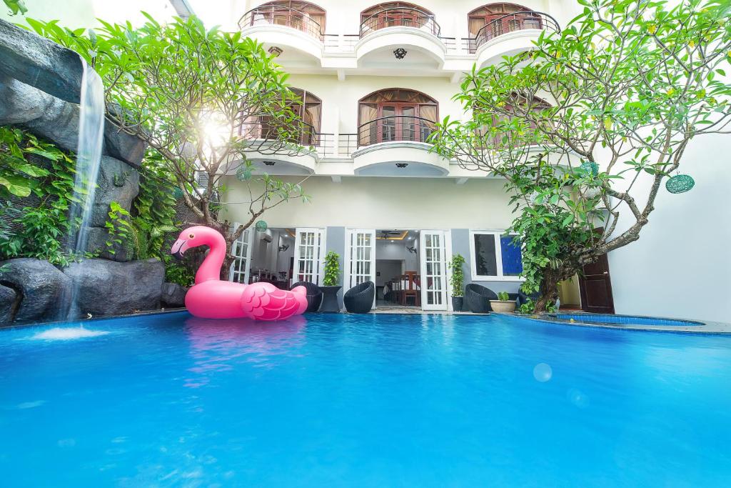 een roze flamingo in een zwembad voor een gebouw bij Gold Coast Hotel Da Nang Hotel in Da Nang