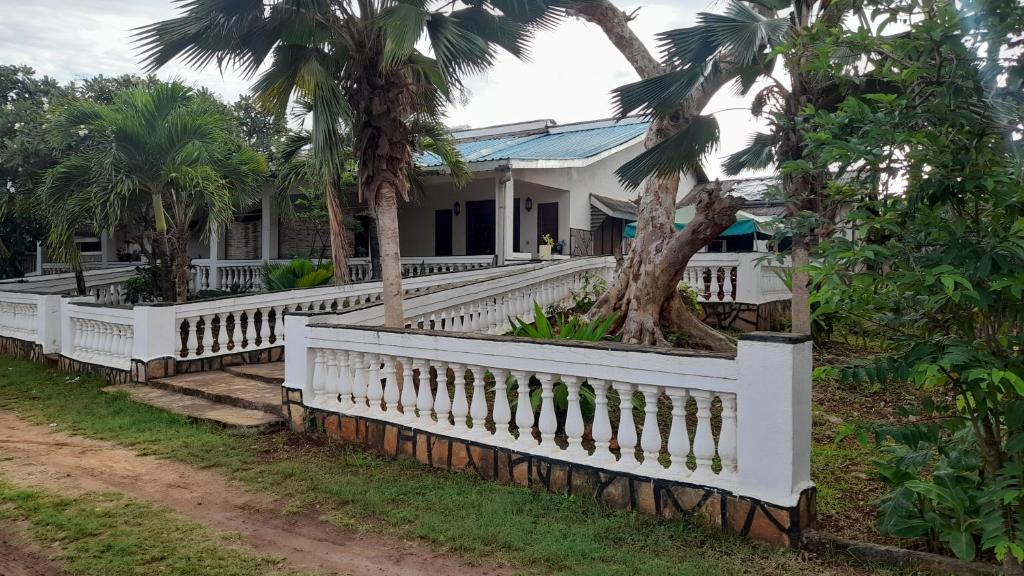 a white fence in front of a house with palm trees at Peters Mansion Bougainvillea Premesis in Mtwapa