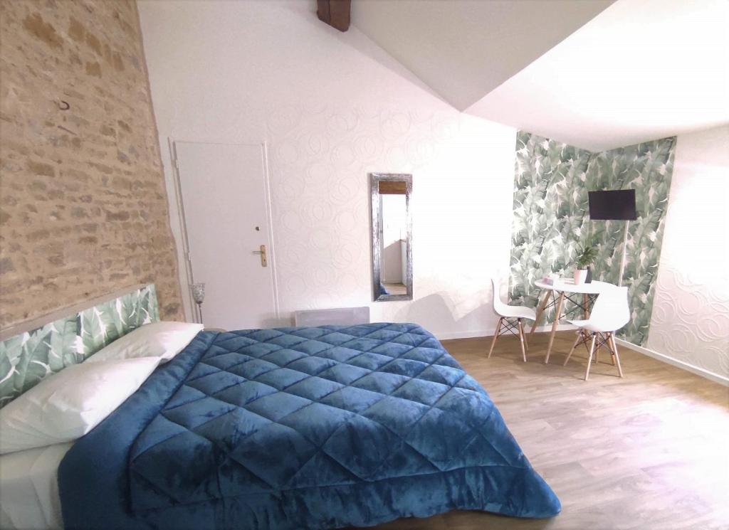 a bedroom with a blue bed and a table at Appartement Oingt - Les Meublés des Pierres Dorées in Theizé