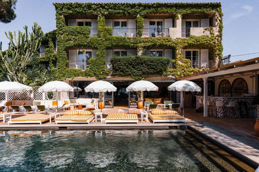 a beach with umbrellas and chairs and a pool at Hotel des Lices in Saint-Tropez