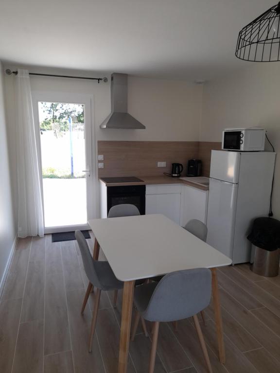 uma cozinha com uma mesa branca e cadeiras em Le Logis de Bonne Anse em Les Mathes