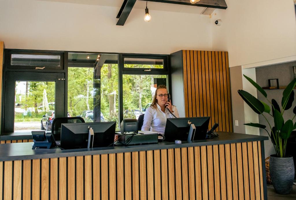 Eine Frau, die auf einem Handy in einem Büro redet. in der Unterkunft EuroParcs Ruinen in Ruinen