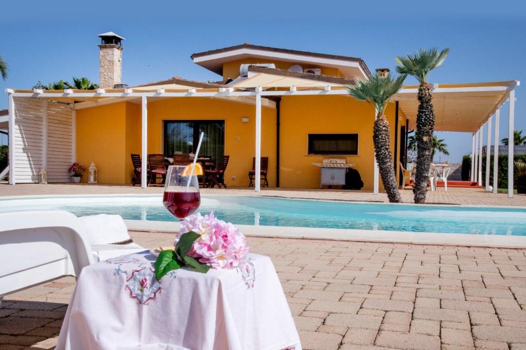 un tavolo con un bicchiere di vino accanto a una casa di Holiday-home-italy a Melissano