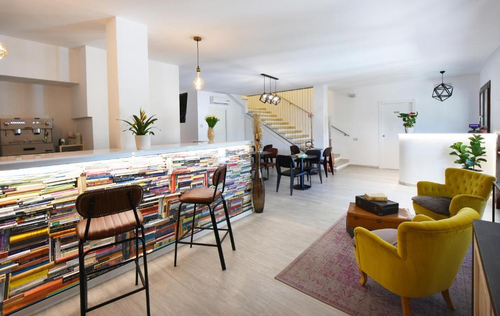 een woonkamer met stoelen en een bar met boeken bij Xenia Hotel in Villasimius