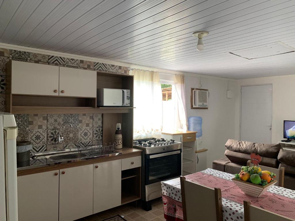 a kitchen and living room with a table and a couch at Casa da Vila in Porto Belo