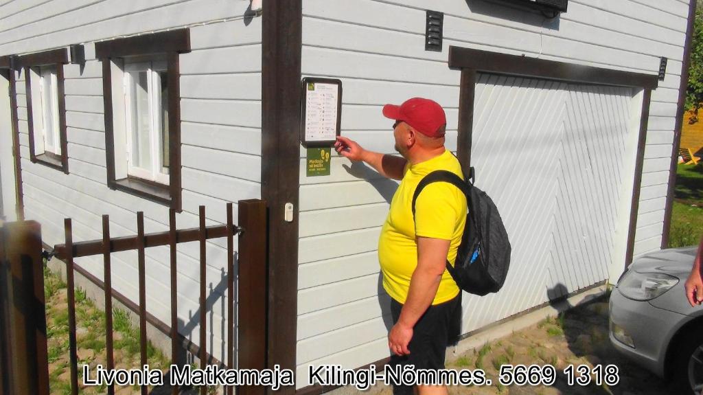 Ein Mann schaut ein Schild auf ein Haus in der Unterkunft Livonia Matkamaja in Kilingi-Nõmme
