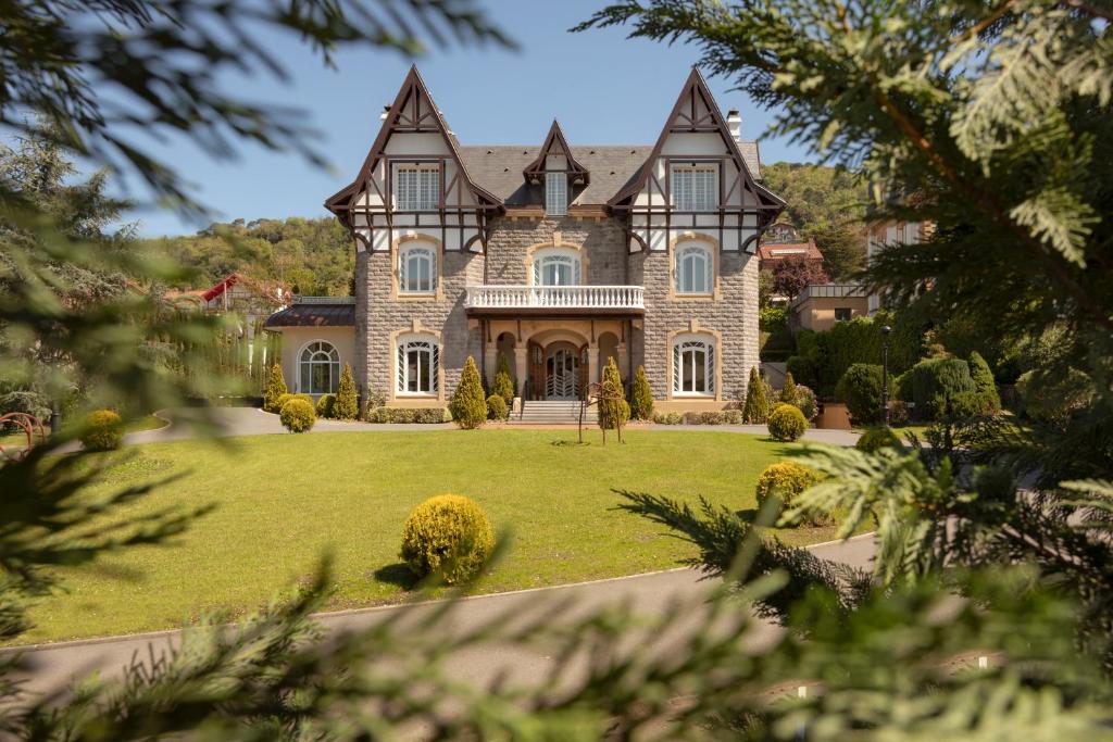 a large house on a lawn with trees at Hotel Villa Soro in San Sebastián