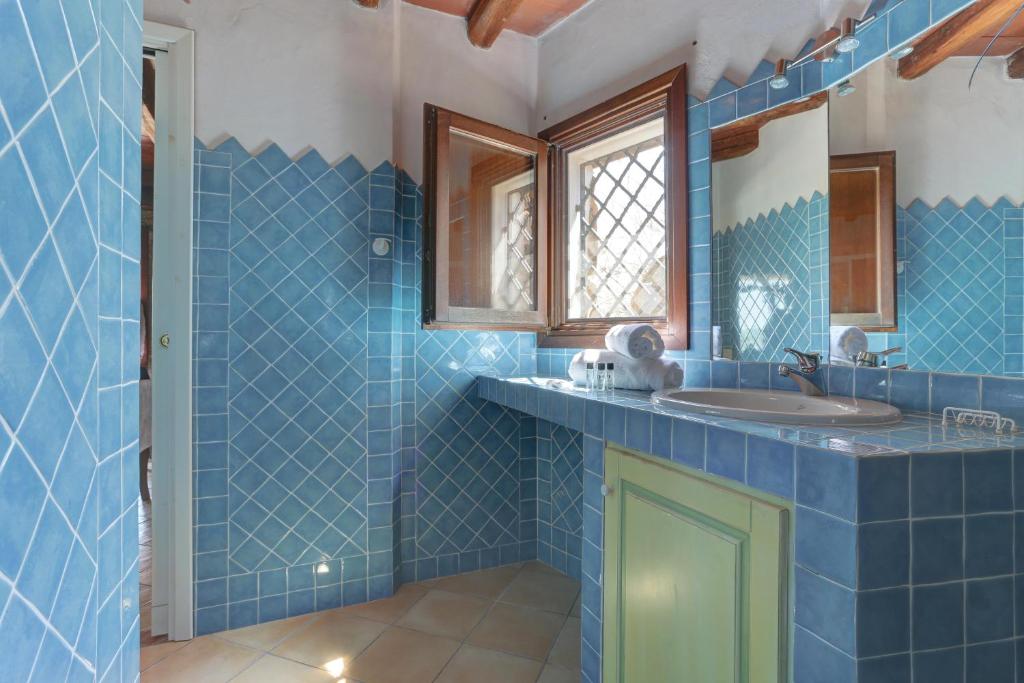 a blue tiled bathroom with a sink and a mirror at VILLA MARIA - CAPO D'ORSO - HOME and MORE in Palau