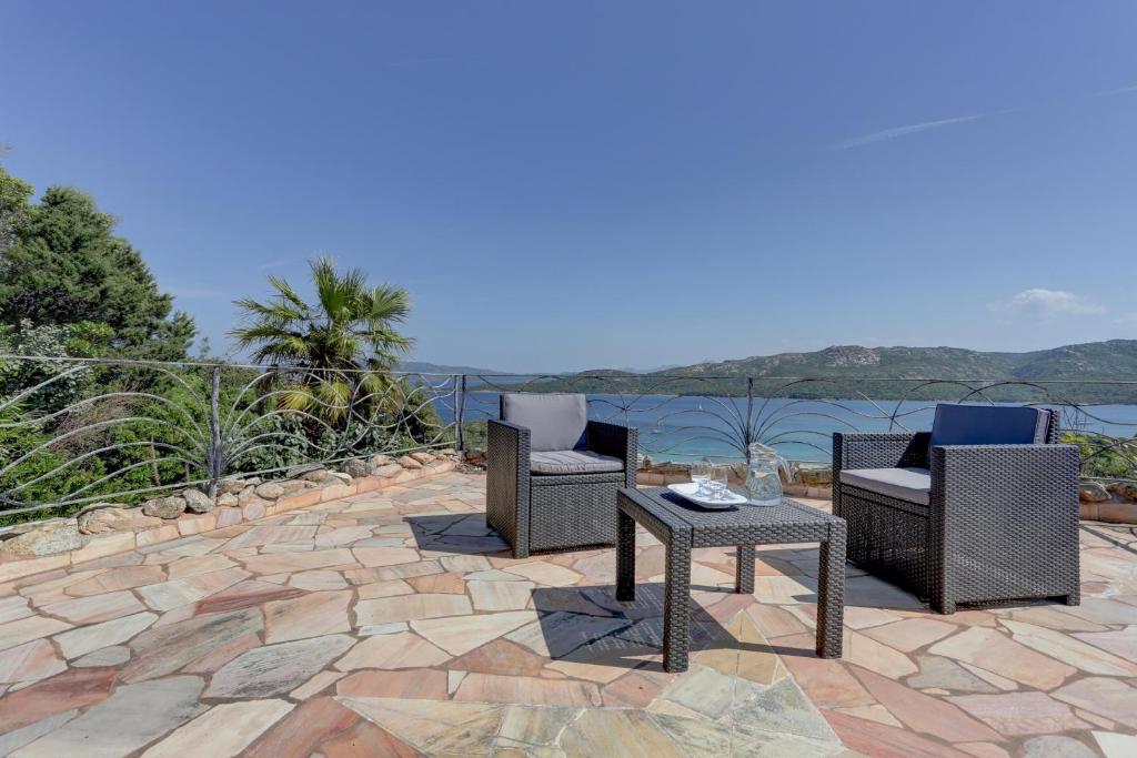 a patio with two chairs and a table with a view of the water at VILLA MARIA - CAPO D'ORSO - HOME and MORE in Palau