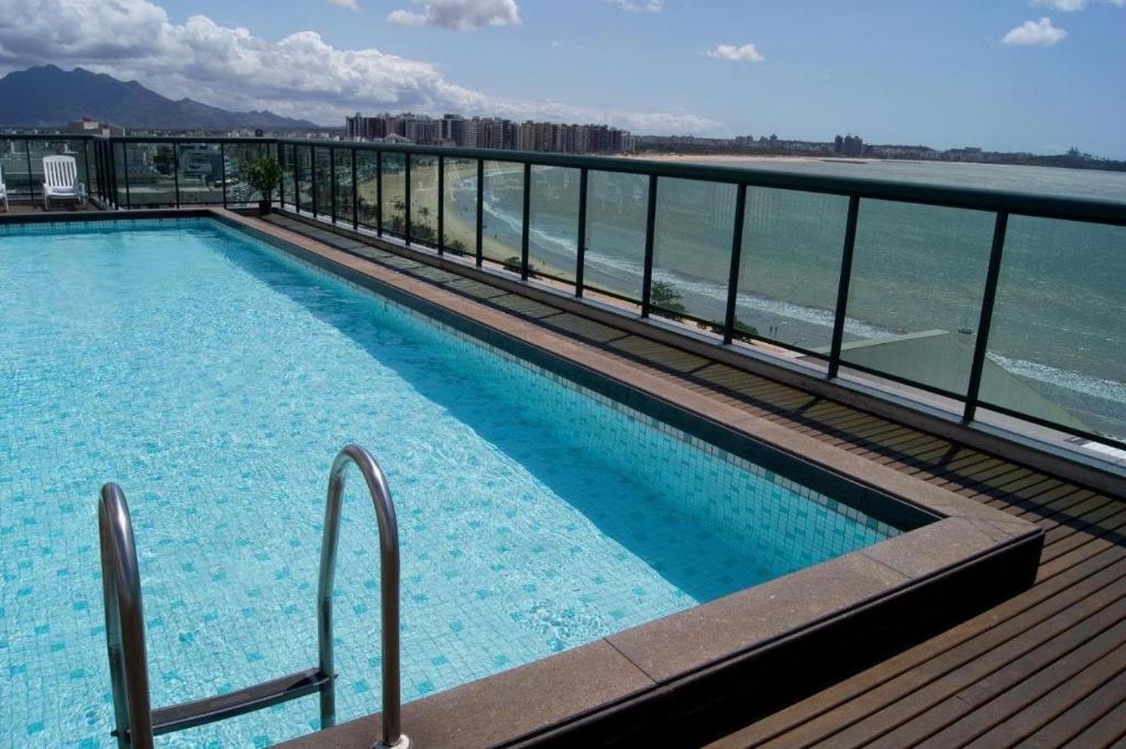 una piscina en la parte superior de un edificio junto al agua en Studio na Praia de Camburi, en Vitória