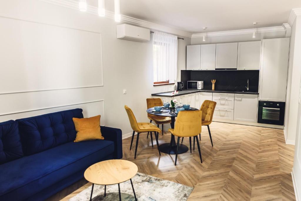 a living room with a blue couch and a table and chairs at Apartamenty Infores Willa Matejki in Przemyśl