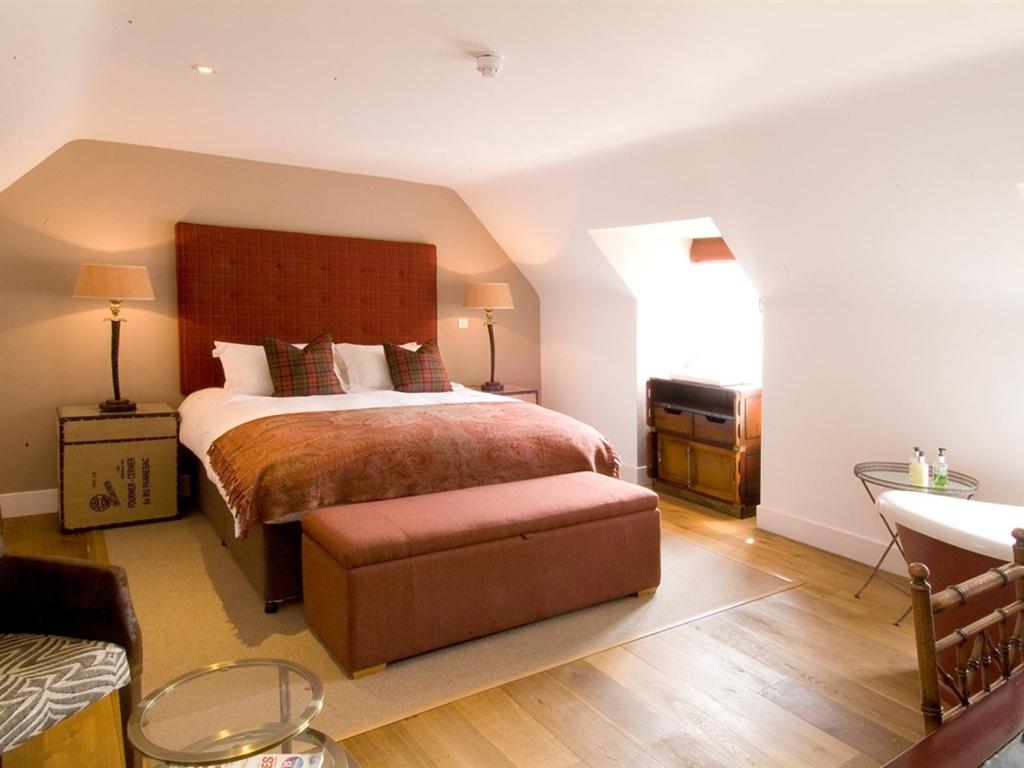 Un dormitorio con una cama grande y un banco. en The Percy Arms en Guildford