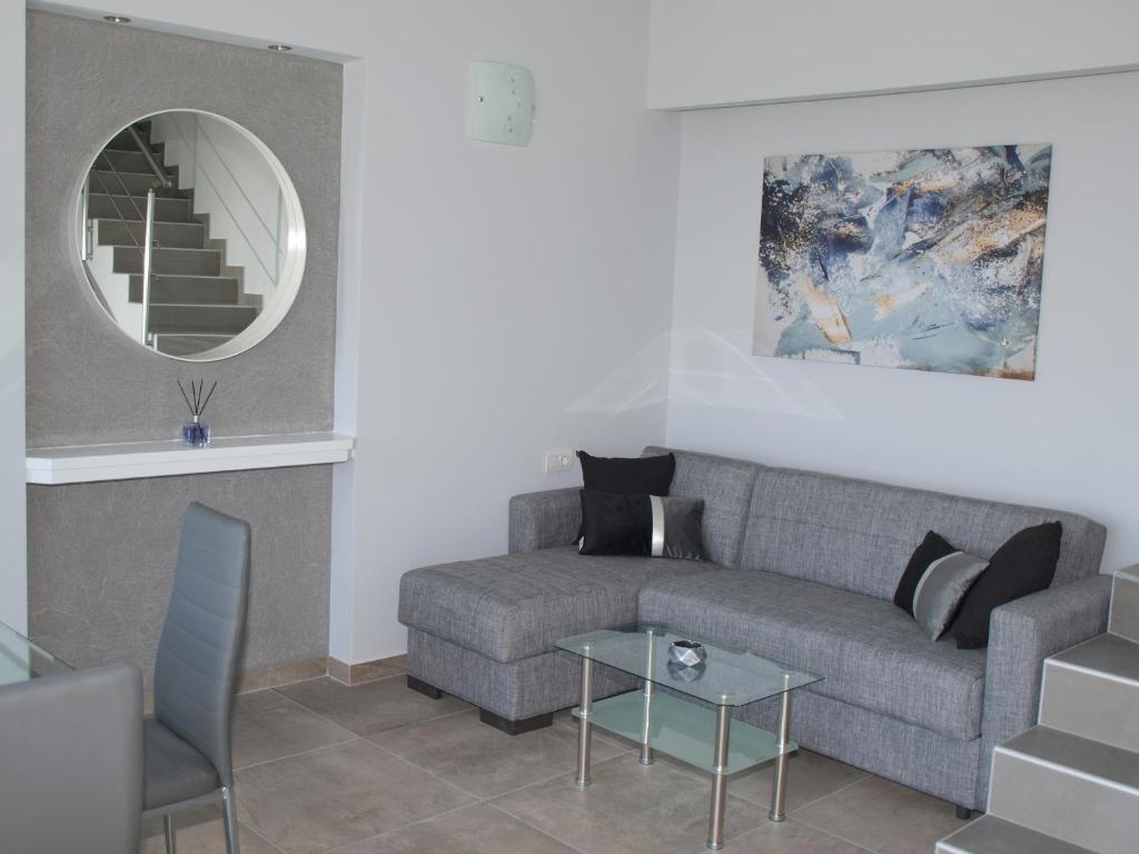 a living room with a couch and a mirror at Attic Apartments in Ayia anna