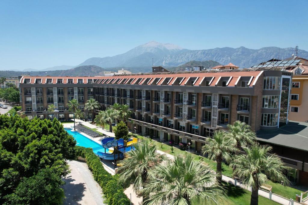 an apartment building with a swimming pool and palm trees at Camyuva Beach Hotel in Kemer