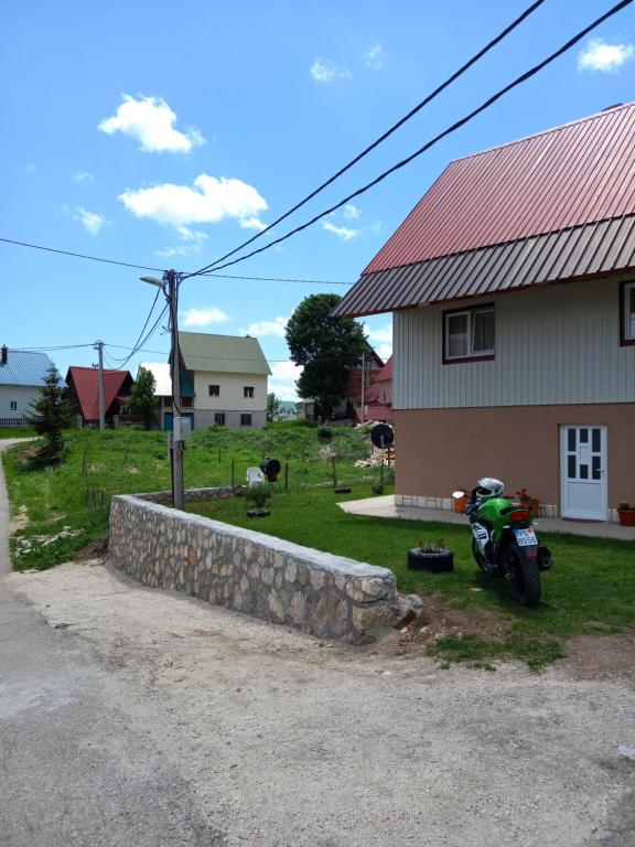 uma moto estacionada em frente a uma casa em Verica Rooms em Žabljak