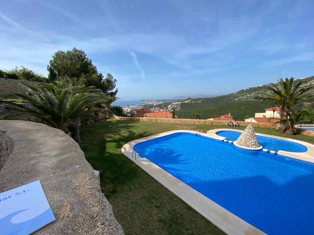 a blue swimming pool in a yard next to a house at Apartamentos Mirador al Mar Altamar in Alcossebre