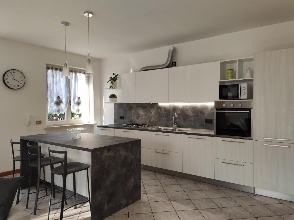 a kitchen with white cabinets and a black counter top at Appartamento nel verde circondato dalle montagne in Vo Sinistro