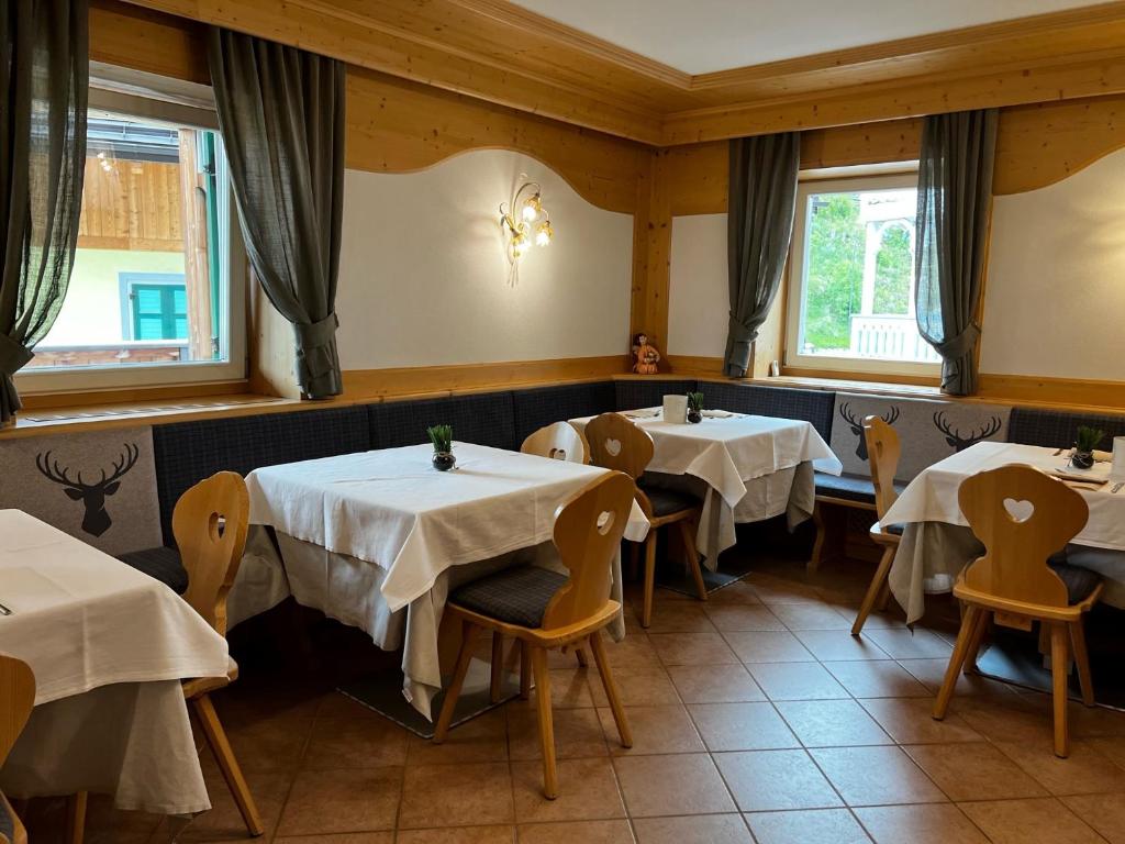 un comedor con mesas, sillas y ventanas en Garnì Villa Elsa en Pozza di Fassa