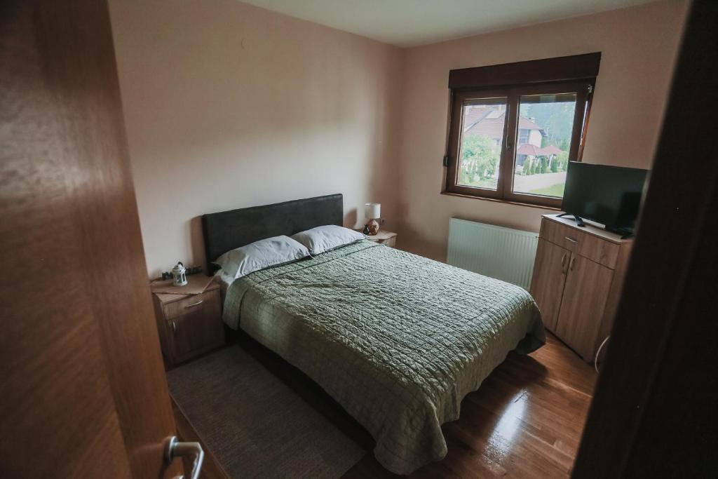 a bedroom with a bed and a window and a television at Apartmani Zračak in Zlatibor