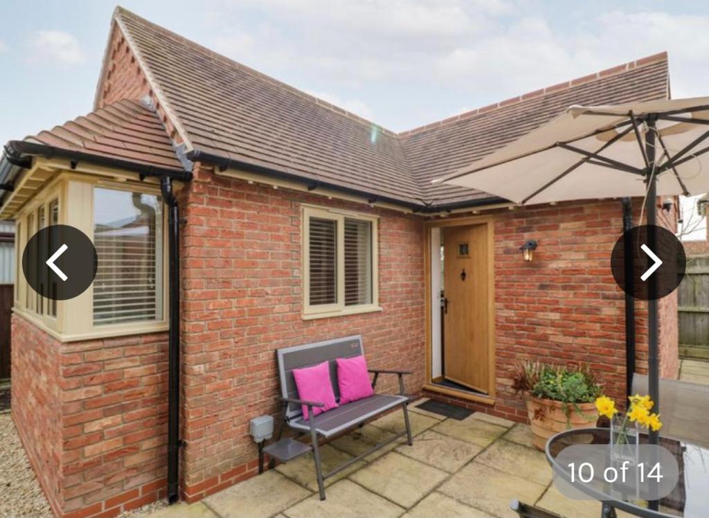 a brick house with an umbrella and a chair on a patio at The Lodge in Eckington