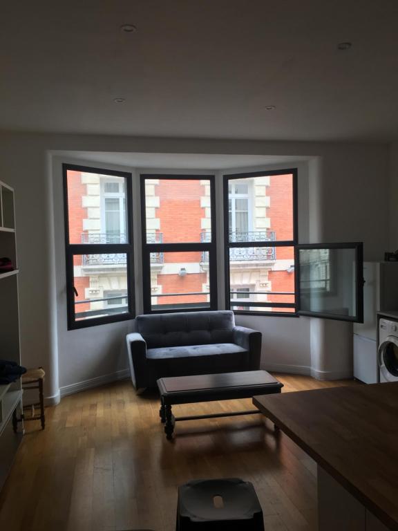 - un salon avec un canapé et quatre fenêtres dans l'établissement Appartement 67 M2 COMEDIE Centre Ville MONTPELLIER, à Montpellier