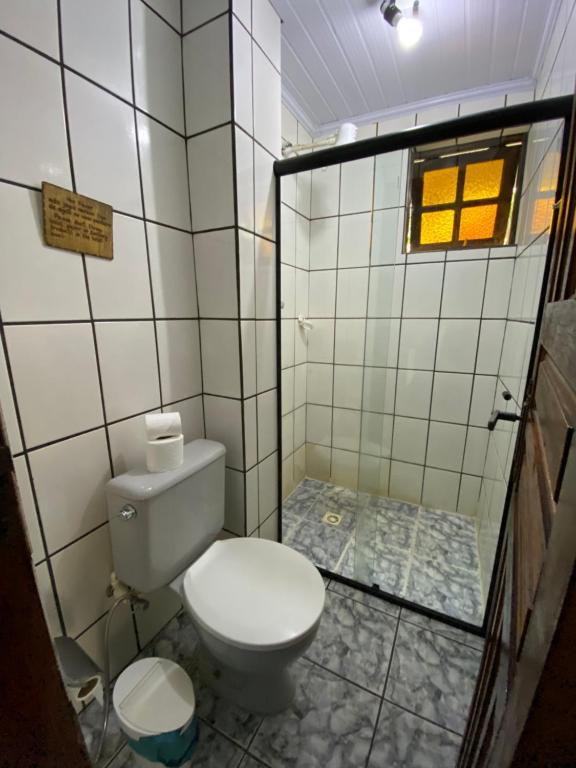 a bathroom with a toilet and a tiled wall at Pousada Canto Verde in Abraão